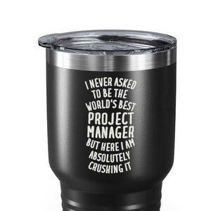 May include: Black stainless steel tumbler with a white inscription that reads "I never asked to be the world's best project manager but here I am absolutely crushing it."
