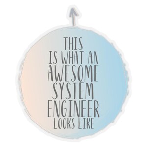 May include: A round sticker with a peach and blue gradient background. The text "THIS IS WHAT AN AWESOME SYSTEM ENGINEER LOOKS LIKE" is in grey. An upward-pointing arrow is at the top of the sticker.
