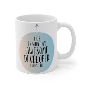 Pode incluir: Caneca de caf&eacute; de cer&acirc;mica branca com um design de aquarela azul e laranja. A caneca tem uma seta apontando para cima e o texto "&Eacute; assim que um desenvolvedor incr&iacute;vel parece".