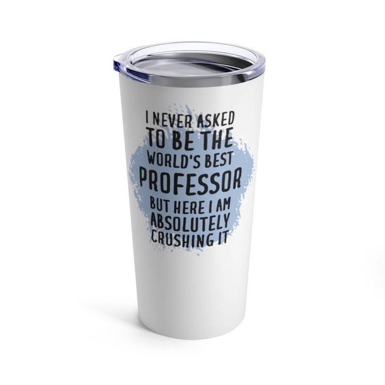 Op de afbeelding: Een witte roestvrijstalen beker met een blauw splatterontwerp en de tekst "Ik heb nooit gevraagd om de beste professor ter wereld te zijn, maar hier ben ik en ik verpletter het absoluut."