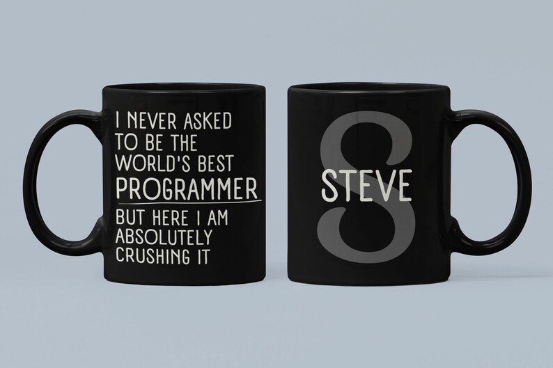Peut inclure: Une tasse &agrave; caf&eacute; noire avec du texte blanc qui dit "Je n'ai jamais demand&eacute; &agrave; &ecirc;tre le meilleur programmeur du monde, mais voil&agrave;, je suis en train de tout &eacute;craser". L'autre c&ocirc;t&eacute; de la tasse a une grande lettre "S" avec le nom "STEVE" en dessous.