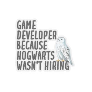 May include: A white sticker with grey text that reads "Game Developer Because Hogwarts Wasn't Hiring". A white snowy owl is to the right of the text.