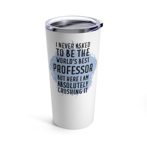 Op de afbeelding: Een witte roestvrijstalen beker met een blauw splatterontwerp en de tekst "Ik heb nooit gevraagd om de beste professor ter wereld te zijn, maar hier ben ik en ik verpletter het absoluut."