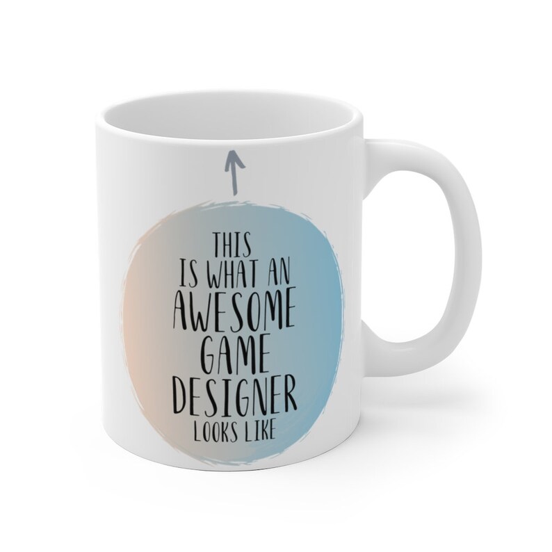 May include: White ceramic coffee mug with a blue and orange watercolor design. The mug has the text "This is what an awesome game designer looks like" on it.