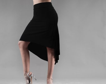 May include: A woman wearing a black high-low skirt with a fitted top. She is wearing silver heels and has her hair pulled back.