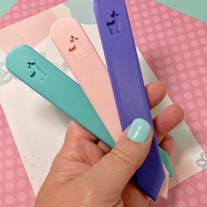 May include: Three plastic bookmark rulers in purple, pink, and light blue. Each bookmark has a small cutout of a house with a chimney.