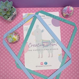 May include: Two light blue and teal diamond-shaped templates, each labeled "A5 8.3" x 5.8", overlay a card with a llama illustration and the text "Creating is fun!" The background is pink with white polka dots.