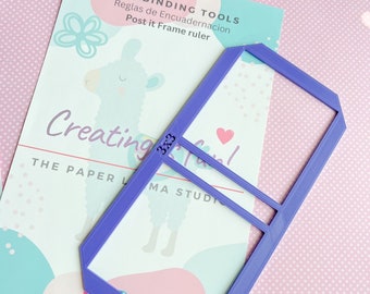 May include: Purple plastic ruler with a frame shape for creating post-it note frames. The ruler has the text "BOOKBINDING TOOLS" and "Reglas de Encuadernacion" on it. The text "Post it Frame ruler" is also on the ruler.