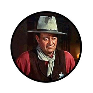 May include: A close-up portrait of a man wearing a brown cowboy hat, a red shirt, and a brown vest. He has a serious expression on his face.