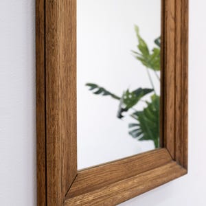 May include: A rectangular mirror with a brown wooden frame. The frame has a slightly distressed look, giving it a vintage feel.
