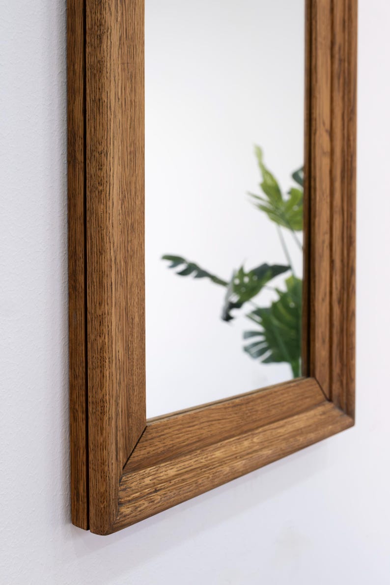 May include: A rectangular mirror with a brown wooden frame. The frame has a slightly distressed look, giving it a vintage feel.