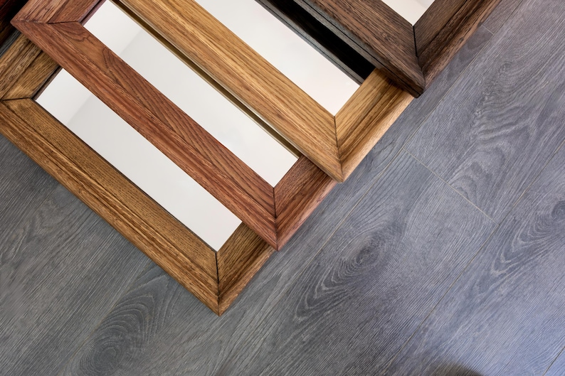 May include: Four wooden picture frames with different wood stains, stacked on top of each other. The frames are all rectangular and have a simple design.