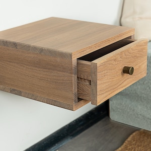 May include: A light brown wooden nightstand with a single drawer that is open. The drawer has a brass knob and is made of the same wood as the nightstand.