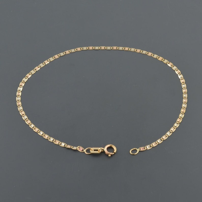 May include: A gold chain bracelet with a tri-color design. The bracelet is made of three different shades of gold: yellow, rose, and white.