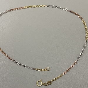 May include: A gold, silver, and rose gold chain necklace with a lobster clasp.