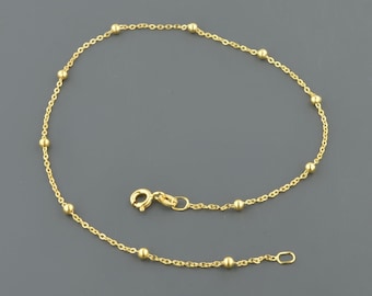 May include: A gold chain anklet with small round beads.