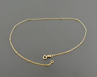 May include: A delicate gold chain anklet with small round beads.