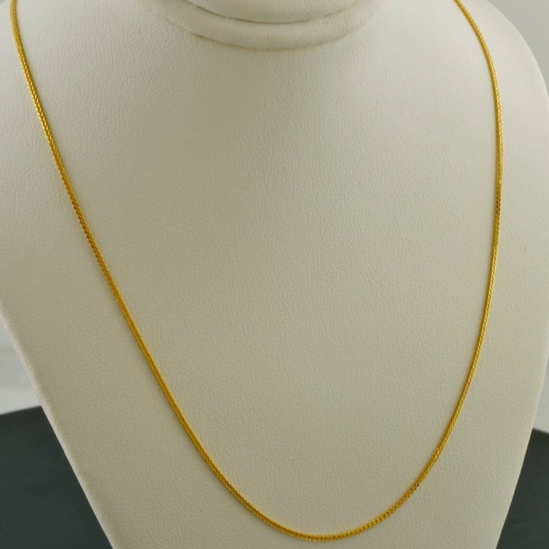 May include: A gold chain necklace with a delicate, braided design. The chain is displayed on a white background.