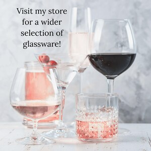 K&ouml;nnte beinhalten: Eine Auswahl an Gl&auml;sern, darunter Weingl&auml;ser, ein Martiniglas mit Kirschen und ein gemusterter Tumbler, die jeweils mit einem anderen Getr&auml;nk gef&uuml;llt sind. Der Text im Bild lautet: "Besuchen Sie meinen Shop f&uuml;r eine gr&ouml;&szlig;ere Auswahl an Glaswaren!"