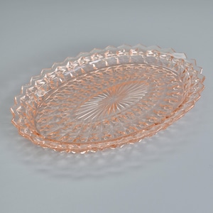 K&ouml;nnte beinhalten: Ein ovales Serviertablett aus rosa Glas. Das Tablett hat eine strukturierte Oberfl&auml;che und einen dekorativen Zickzackrand. Die Mitte des Tabletts hat ein Sternmuster. Dieses Vintage-St&uuml;ck ist ideal zum Servieren von Vorspeisen oder Desserts, ca. 30 cm lang.