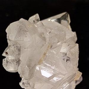 May include: A cluster of clear quartz crystals with a variety of shapes and sizes. The crystals are arranged in a random pattern and have a natural, rough texture.