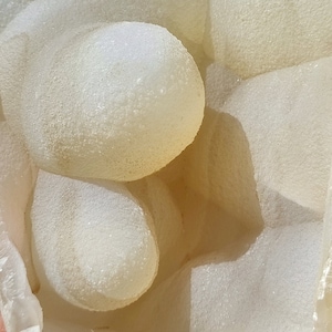 May include: A white agate geode with a smooth, textured surface. The geode is open, revealing a cluster of smaller, round agate nodules inside.