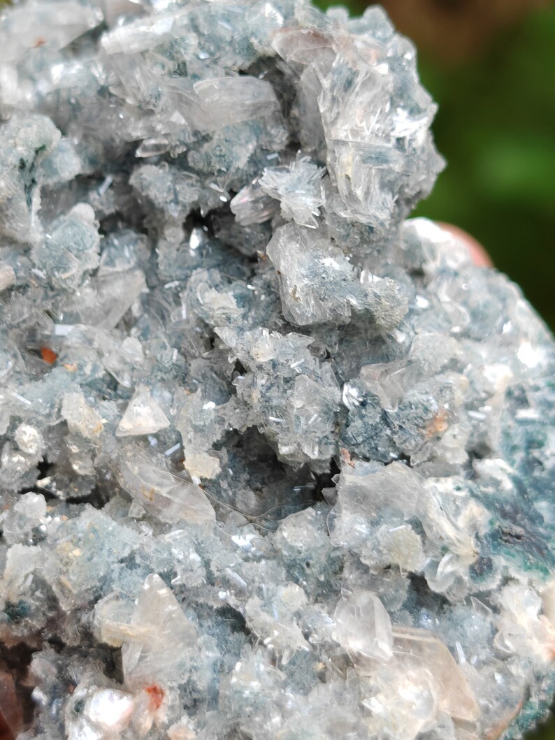 May include: A cluster of clear, sparkling crystals with a light blue, green, and grey base. The crystals are arranged in a random, natural pattern.