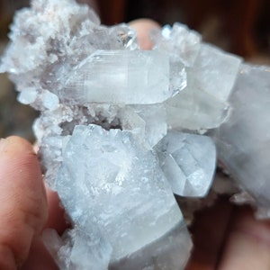 Könnte beinhalten: Ein Cluster aus klaren, hellblauen Kristallen mit einer weißen, undurchsichtigen Basis. Die Kristalle sind scharf und kantig, mit einem durchscheinenden Aussehen.