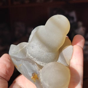 May include: A light gray agate geode with a smooth, rounded surface. The geode has a natural, organic shape and is a beautiful example of a natural crystal formation.