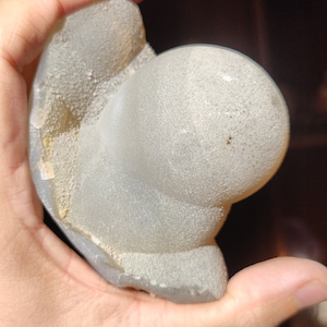 Peut inclure: Une g&eacute;ode blanche de forme irr&eacute;guli&egrave;re avec une surface rugueuse et textur&eacute;e. La g&eacute;ode est partiellement ouverte, r&eacute;v&eacute;lant un int&eacute;rieur cristallin.