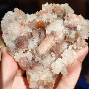 Könnte beinhalten: Ein Cluster aus weißen und braunen Kristallen mit einer rauen, strukturierten Oberfläche. Die Kristalle sind in einem zufälligen Muster angeordnet und haben ein natürliches, organisches Aussehen.