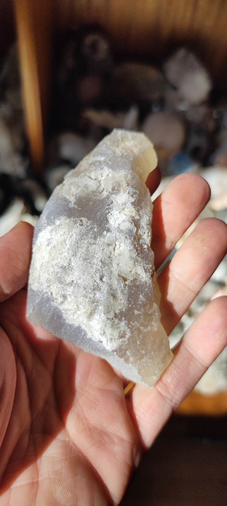 K&ouml;nnte beinhalten: Ein hellgrauer Achat-Stein mit wei&szlig;en B&auml;ndern und einer rauen, strukturierten Oberfl&auml;che.