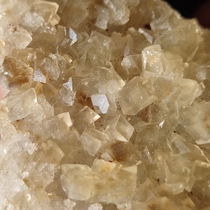 Pu&ograve; includere: Un gruppo di cristalli traslucidi di colore marrone chiaro con una texture ruvida e naturale.