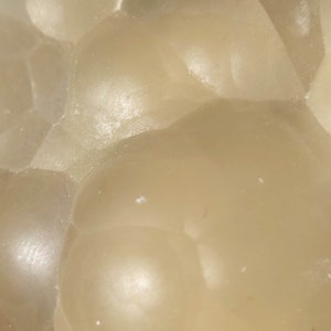 K&ouml;nnte beinhalten: Nahaufnahme eines hellbeigen, durchscheinenden und glatten Steins mit einer strukturierten Oberfl&auml;che. Der Stein hat ein nat&uuml;rliches, organisches Aussehen und Gef&uuml;hl.