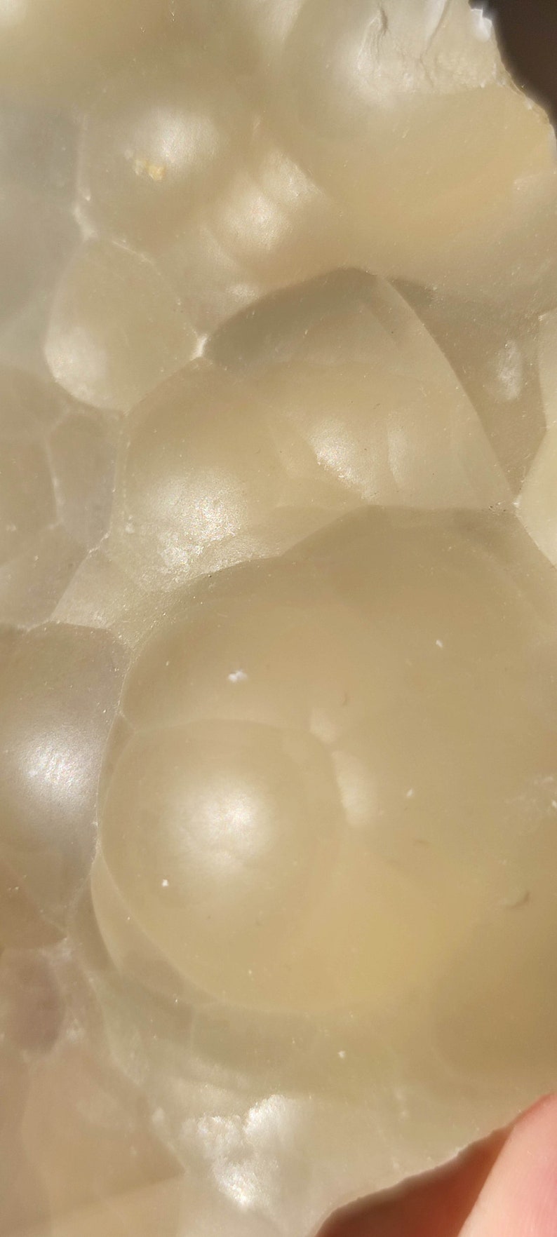 K&ouml;nnte beinhalten: Nahaufnahme eines hellbeigen, durchscheinenden und glatten Steins mit einer strukturierten Oberfl&auml;che. Der Stein hat ein nat&uuml;rliches, organisches Aussehen und Gef&uuml;hl.