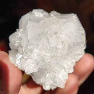 May include: A cluster of clear quartz crystals with a rough, natural texture. The crystals are clustered together in a random formation, creating a unique and interesting piece.