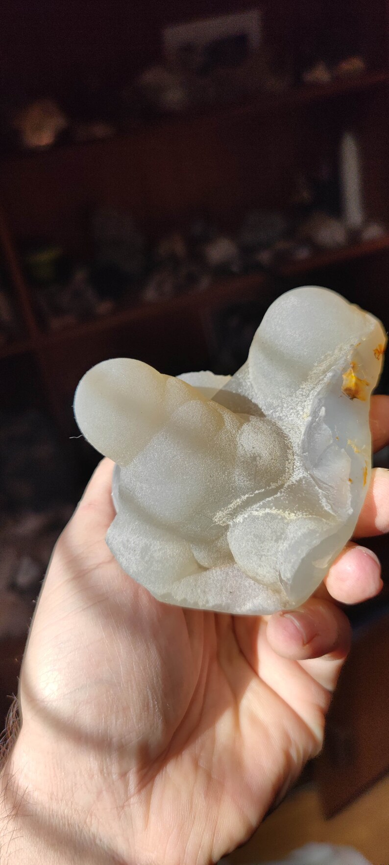 May include: A white agate geode with a smooth, rounded surface and a light brown interior. The geode is a natural formation with a unique shape and texture.