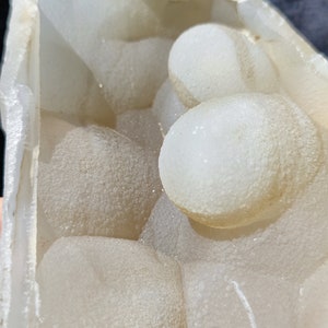 May include: A geode with a white, translucent exterior and a cluster of smaller, round, white crystals inside.