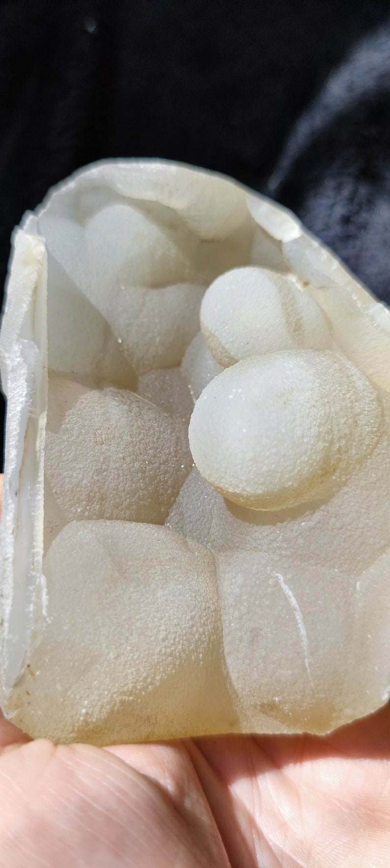 May include: A geode with a white, translucent exterior and a cluster of smaller, round, white crystals inside.