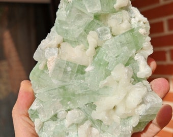 May include: A cluster of green celestite crystals with white calcite crystals. The crystals are arranged in a cluster, with the green celestite crystals being the most prominent. The crystals are translucent and have a glassy luster.