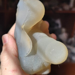 May include: A white agate geode with a smooth, translucent surface. The geode has a unique, organic shape and is a beautiful example of natural beauty.