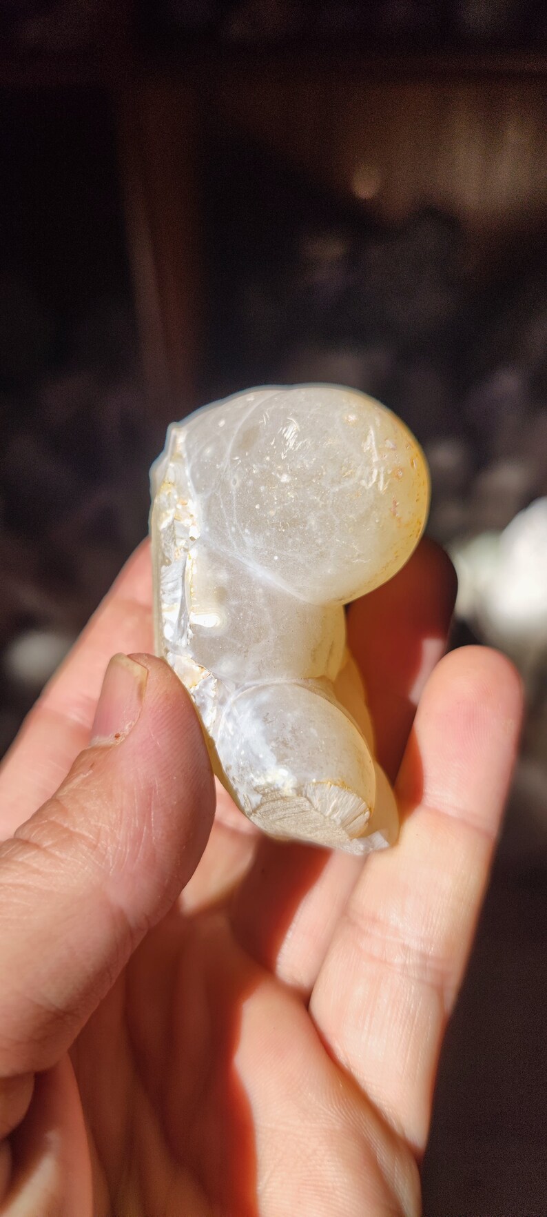 Może przedstawiać: Biała geoda agatowa o gładkiej, zaokrąglonej powierzchni i naturalnej, szorstkiej fakturze. Geoda ma jasnobrązowy kolor na krawędziach i białe wnętrze.