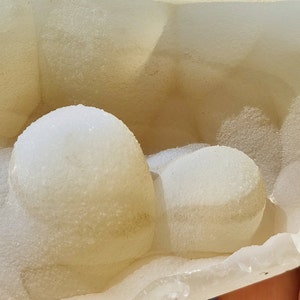 May include: A close-up of a white, translucent, geode with a rough, textured surface. The geode is filled with small, white, crystal formations.