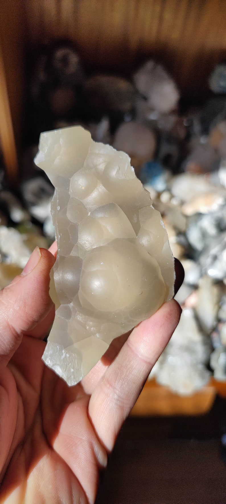 K&ouml;nnte beinhalten: Ein durchscheinender wei&szlig;er Achat mit einer blasigen, strukturierten Oberfl&auml;che. Der Achat hat eine milchig wei&szlig;e Farbe und ist unregelm&auml;&szlig;ig geformt.