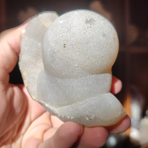 Peut inclure: Une g&eacute;ode d'agate blanche, ronde et textur&eacute;e avec une surface lisse et polie. La g&eacute;ode a la forme d'une petite colline arrondie.