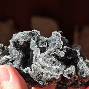 May include: A cluster of gray and green chalcedony with a rough, textured surface. The chalcedony has a translucent appearance with a hint of blue.