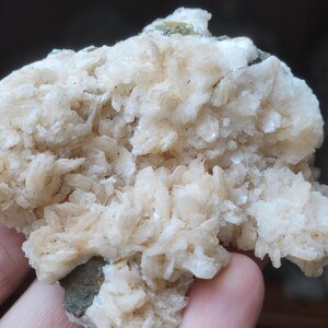 Könnte beinhalten: Ein Cluster aus weißen und beigefarbenen Barytkristallen mit einer rauen, strukturierten Oberfläche. Die Kristalle sind in einer geschichteten Formation angeordnet, was ein visuell interessantes und einzigartiges Exemplar ergibt.