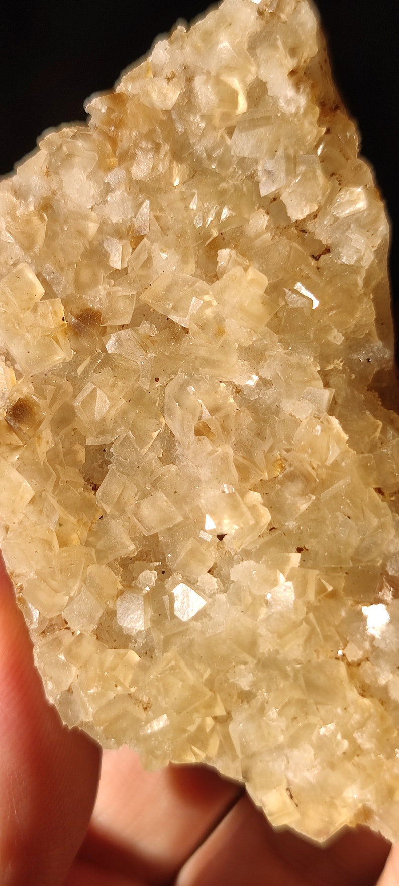 Pu&ograve; includere: Un ammasso di cristalli traslucidi di colore marrone chiaro con una texture ruvida e naturale. I cristalli sono disposti in uno schema denso e irregolare, creando un pezzo visivamente interessante e unico.