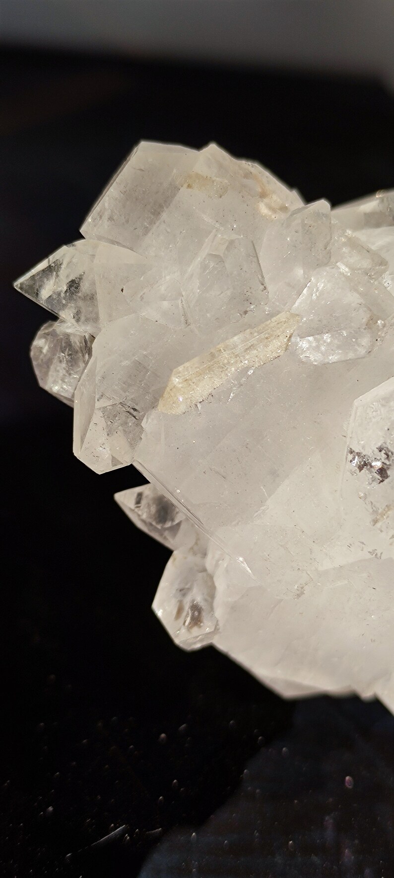 May include: A cluster of clear quartz crystals with a pointed shape. The crystals are arranged in a cluster, with some of the crystals pointing upwards and others pointing downwards. The crystals are translucent and have a slight sparkle.