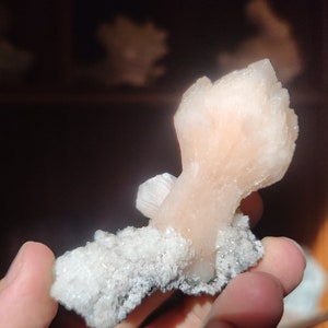 Könnte beinhalten: Ein rosa-weißer Kristallcluster mit einer rauen, strukturierten Oberfläche. Der Kristall ist eine natürliche Formation mit einer einzigartigen Form.